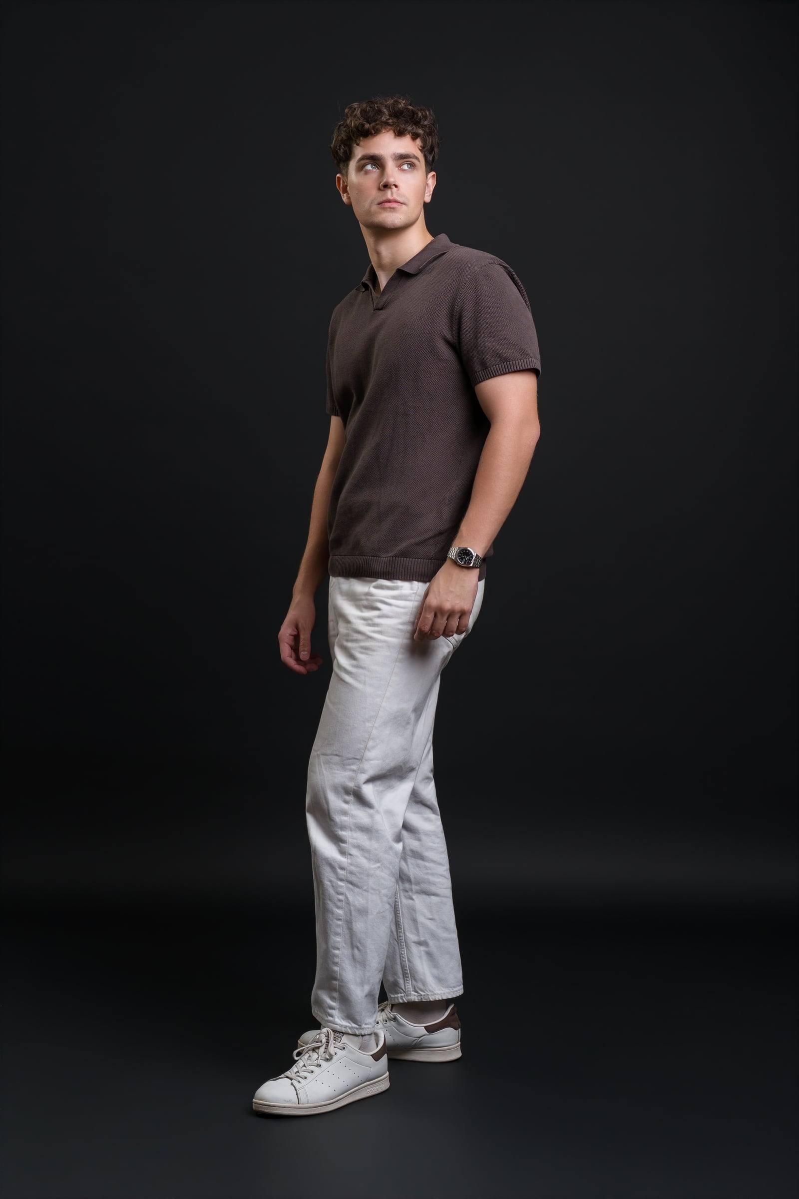 Jorge Tyrakowski in a brown knit polo and light trousers, full length, looking to the side